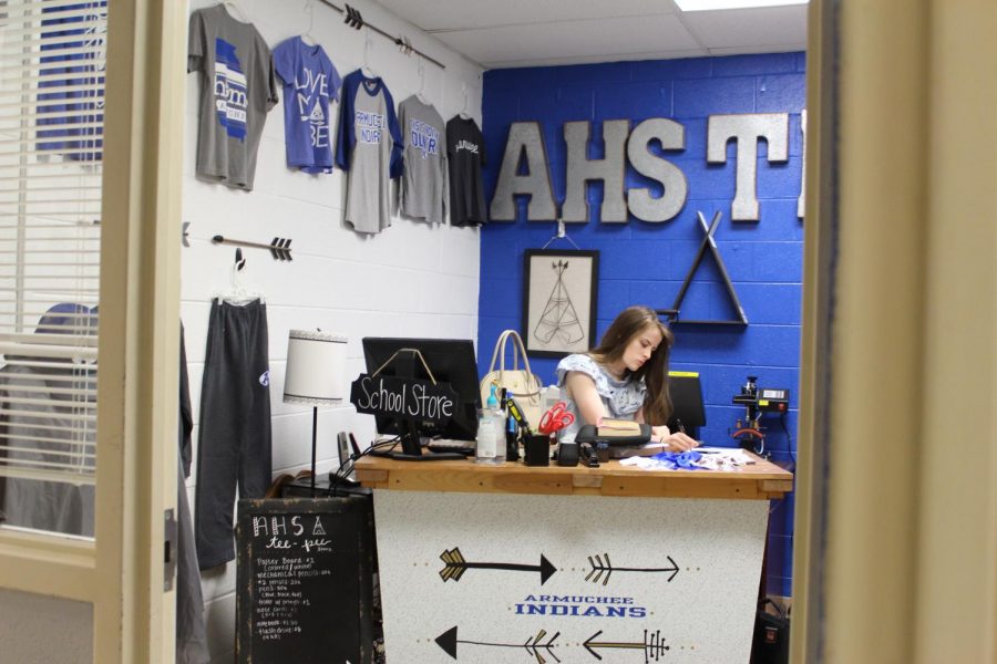 This photo has captured a student intern working in the TeePee store. It displays the merchandise we have to pick from and the prices that they cost. With the blue paint on the walls and the school colors all over the room, the TeePee store radiates school spirit.