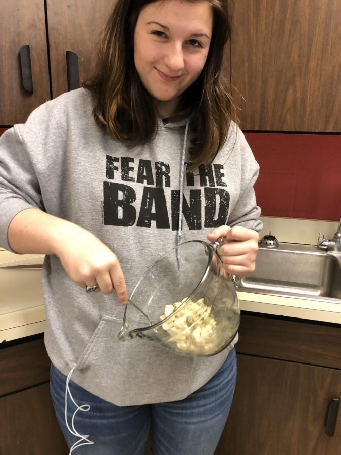 In this photo, junior Victoria Merrit is also following the recipe and is mixing the dough with the butter and dill mixture. 