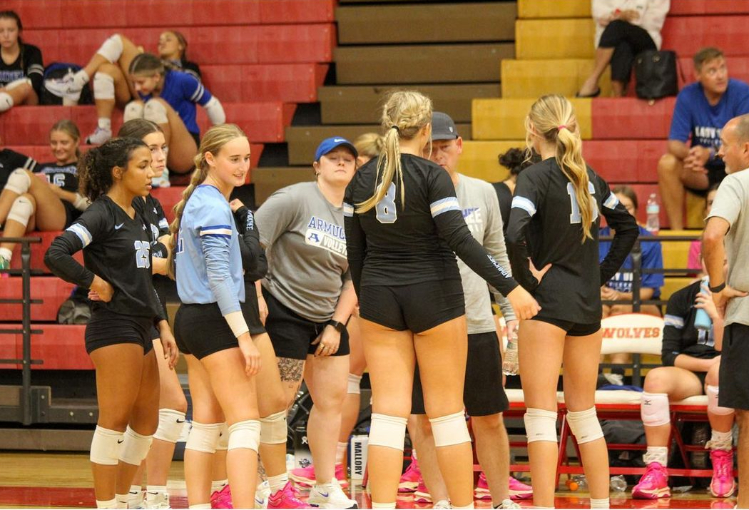 Coach Decker and Coach Wacker in a huddle with Taylor Burns, Sophie Thacker, Chrissy Brynteson, Taylor Ragland, and Ella Dehart