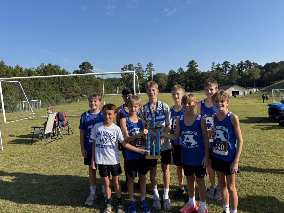 AMS boys XC team proudly holding their trophy after a meet.